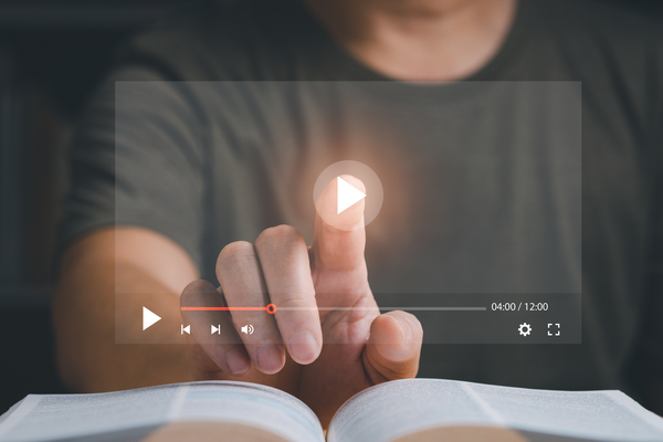 Finger tippt auf Play-Button auf dem Bildschirm, symbolisiert Start des YouTube Videos.