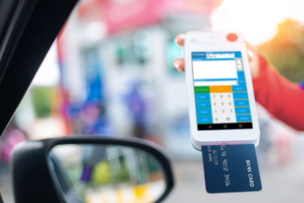 Mitarbeiter kassiert mit mobilem POSMANpop Gerät und EC-Karte am Auto: Schnelle Bon-Vorerfassung und kontaktloses Bezahlen im Baustoffhandel.